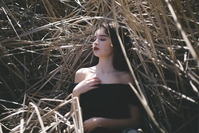 穿黑色露肩上衣的女人躺在干草堆里